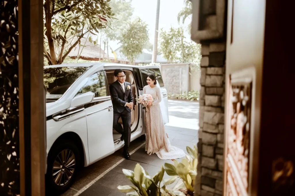 Pasangan pengantin turun dari Toyota Alphard putih sebagai wedding car di Bali